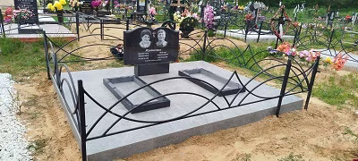 Двойной памятник на бетонном подиуме с металлической оградой